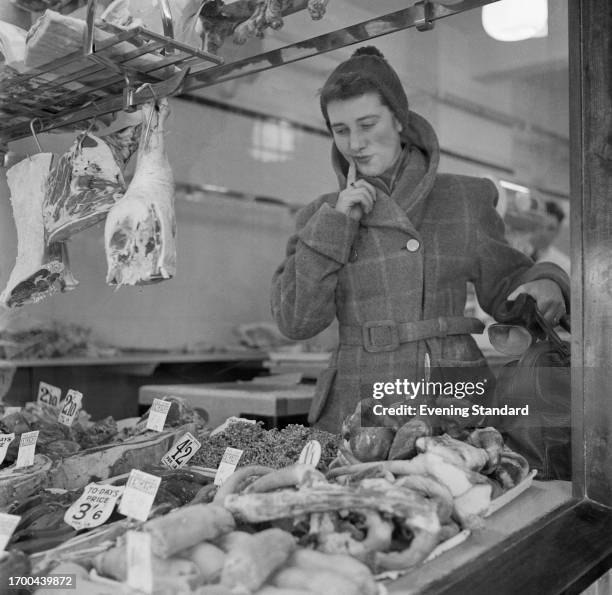 Mrs Barbara Ball choosing meat at butcher's shop, February 26th, 1957.