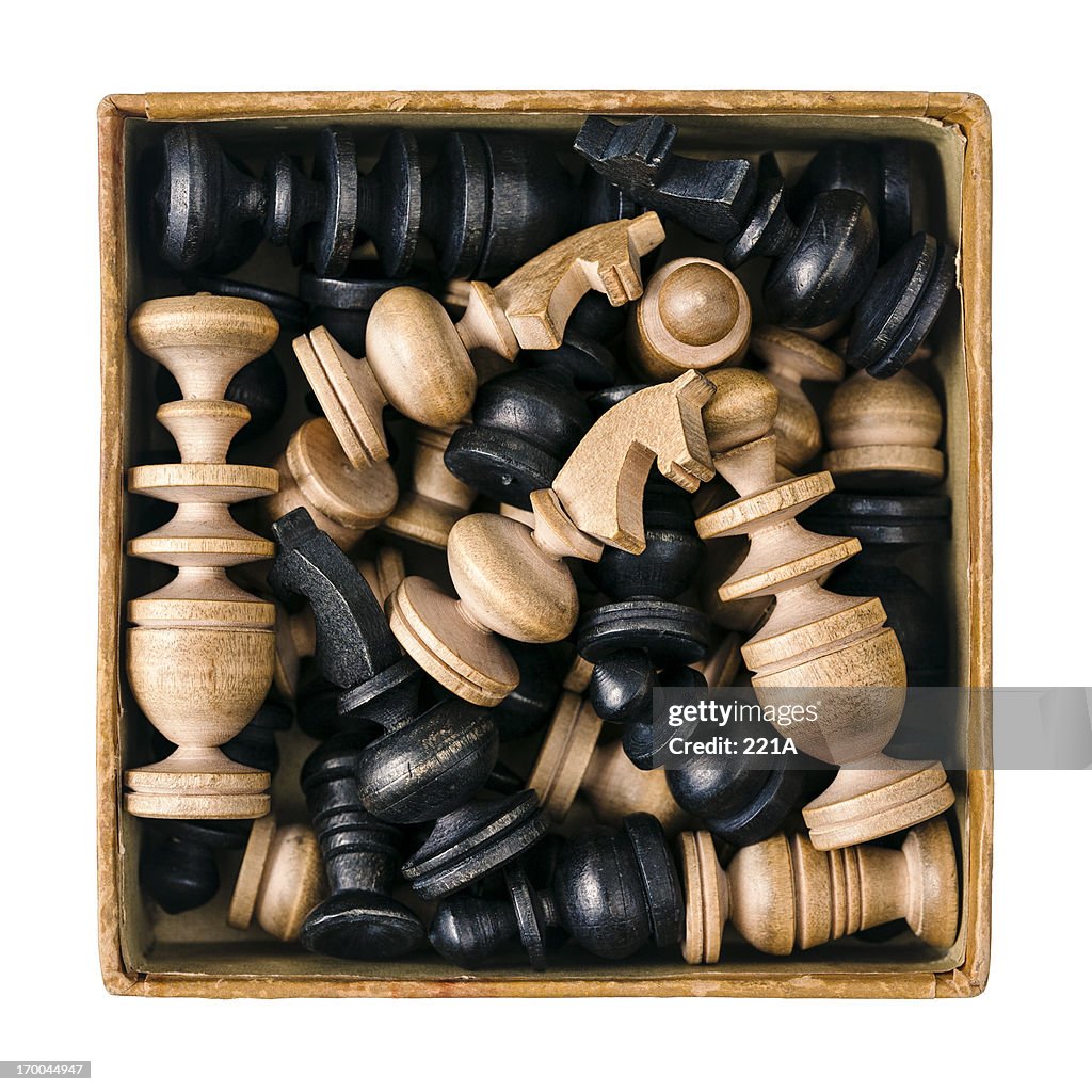 Box of antique chess pieces on white