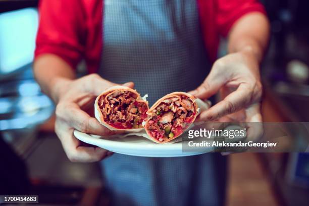 ordentlich verpackte pita-stücke mit zutaten im inneren, die den perfekten döner kebab präsentieren - shawarma stock-fotos und bilder