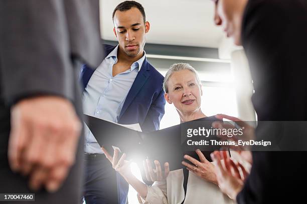 mature businesswoman leading a meeting - old woman young man stock pictures, royalty-free photos & images