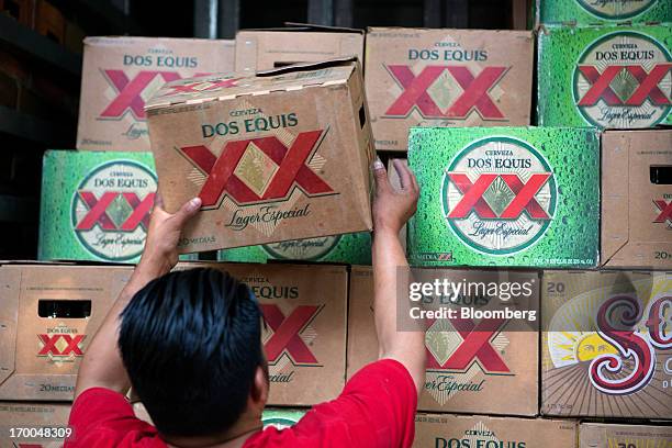 Worker unloads a case of Grupo Modelo SAB's Dos Equis brand beer from a truck operated by Cuauhtemoc-Moctezuma, a subsidiary of Heineken NV, while...