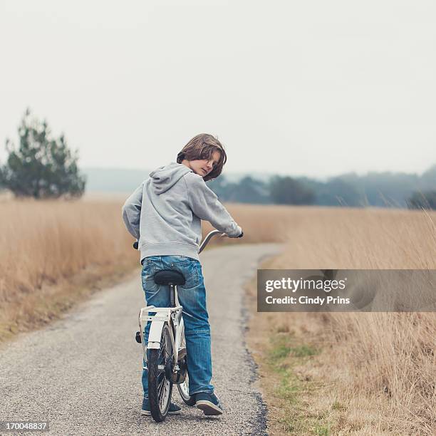 boy on a bicycle looking over his back - boy looking over shoulder stock pictures, royalty-free photos & images