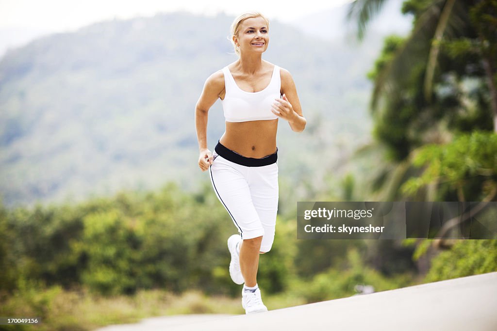 Sporty young woman running up the hill.