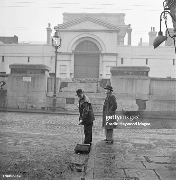 Man sweeps the road opposite Pentonville Prison, London, 1952. Original Publication: Picture Post - 6067 - Pentonville Prison - unpub.