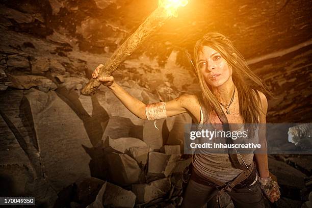 female heroine looking in a cave with torch - cave fire stock pictures, royalty-free photos & images