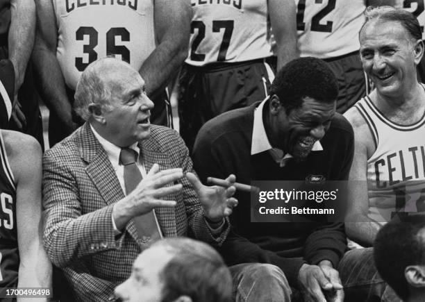 Former Boston Celtics' players Bill Russell and Bob Cousy laugh while listening to their former coach Arnold 'Red' Auerbach on the sidelines during a...