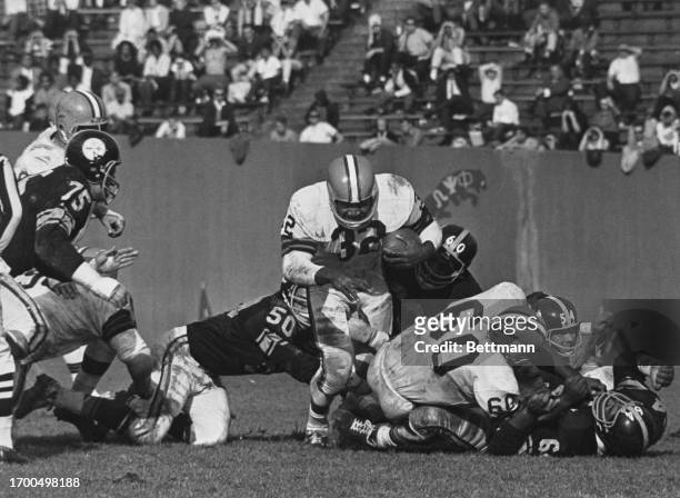 Cleveland's Jim Brown steps over teammate John Wooten , before being tackled by the Steelers' Bill Saul and Ben McGee in the second quarter of a game...