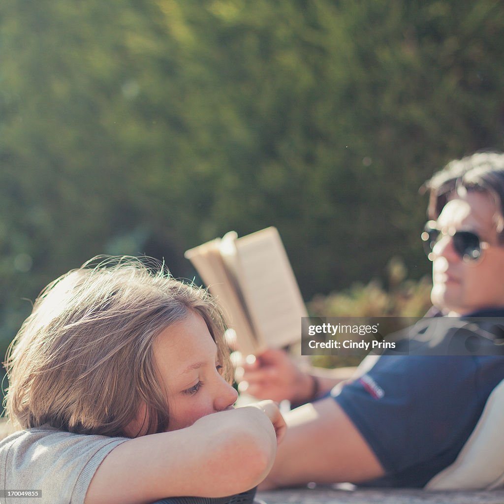 Father and son in the garden reading a book