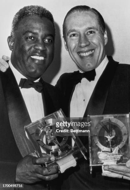 Jackie Robinson and Bob Feller smile as they pose with clocks presented to them at the 23rd annual Boston Baseball Writers' dinner in Boston, January...