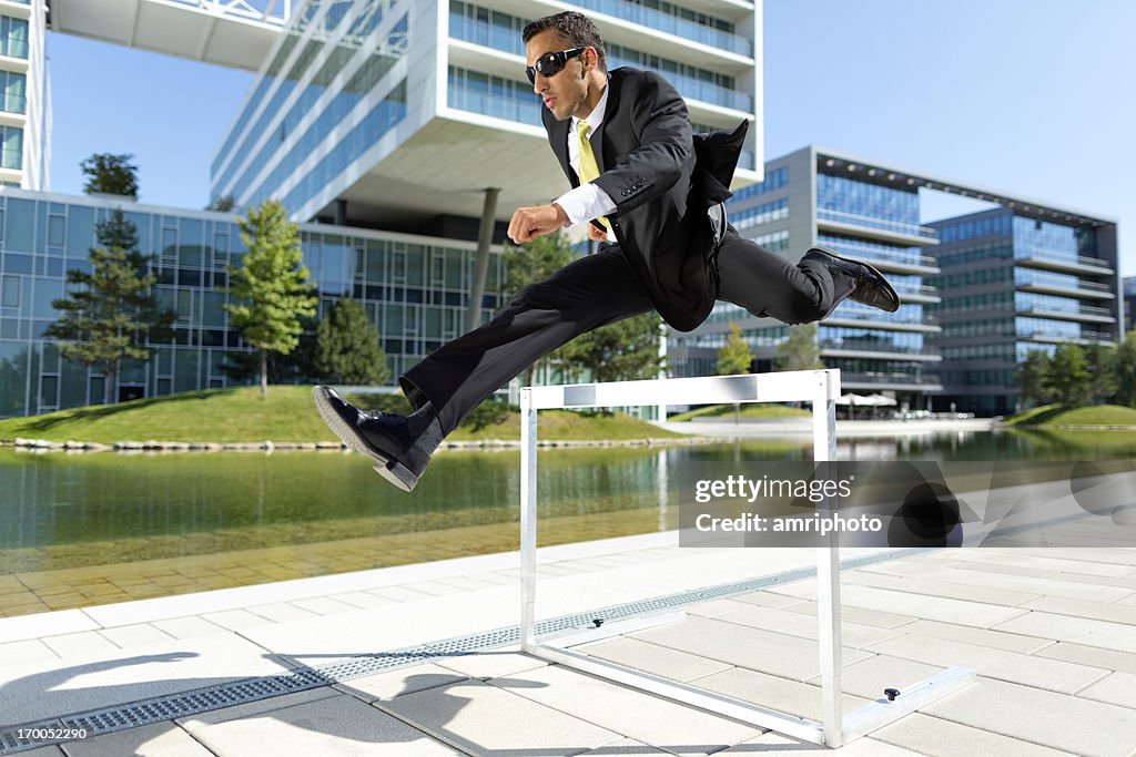 Business Mann über die Hürde in der Nähe von Firmenbüros