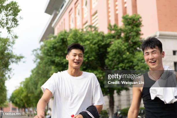 two male college students walking on campus - 成年人 stockfoto's en -beelden