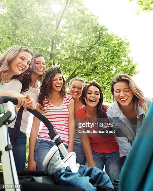 young women smiling to a baby - tienerzwangerschap stockfoto's en -beelden