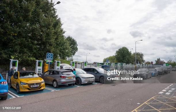 Drivers queue in their EV electric cars to re-charge at a charging point at Moto Exeter M5 Motorway Services on September 23, 2023 in Exeter, England.