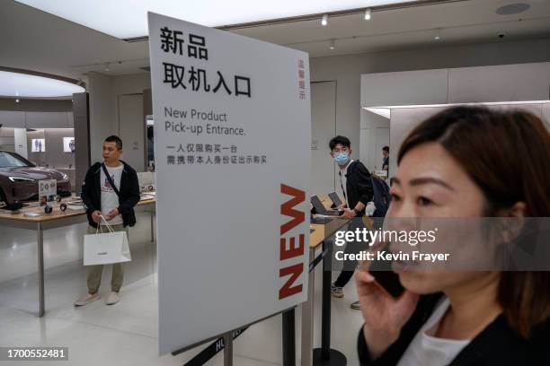 Man carries a bag with a new Mate 60 smartphone as others shop in the new product area of a Huawei flagship store after the company unveiled new...