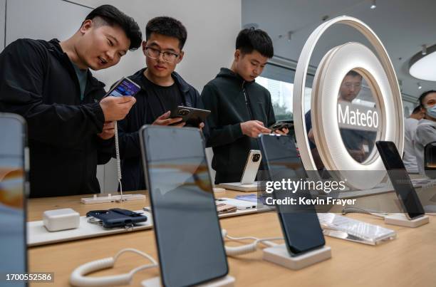 People look at newly launched smartphones at a Huawei flagship store after the company unveiled new products on September 25, 2023 in Beijing, China....