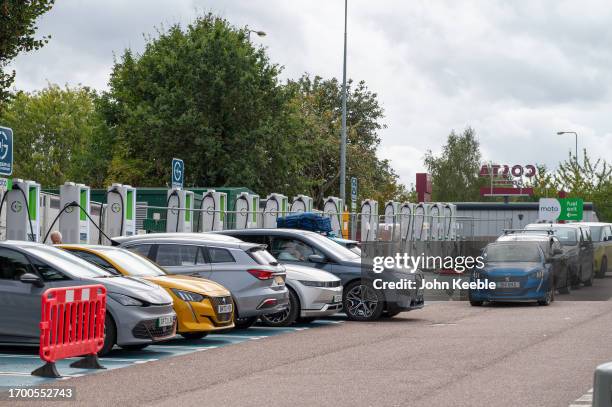 Exeter M5 Services Postcode Drivers queue in their EV electric cars to re-charge at a charging ...