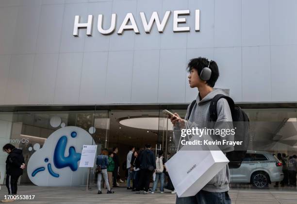 Man walks with bag after making a purchase at a Huawei flagship store after the company unveiled new products on September 25, 2023 in Beijing,...