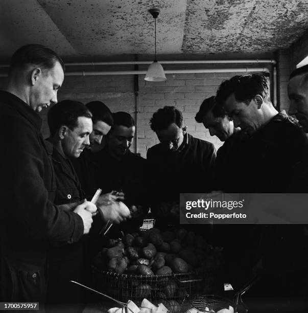 German prisoners of war peel potatoes in the cookhouse at Wilton Park POW camp, known as Camp 300, near Beaconsfield in Buckinghamshire, England in...