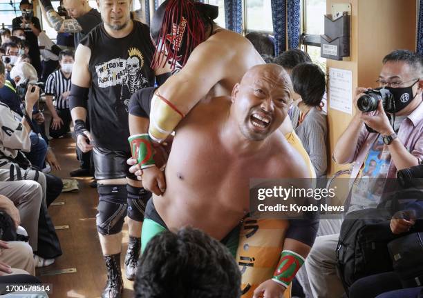 Passengers watch pro wrestlers fight inside a moving train on Yamagata Railway's Flower Nagai Line running in the southern part of Yamagata...