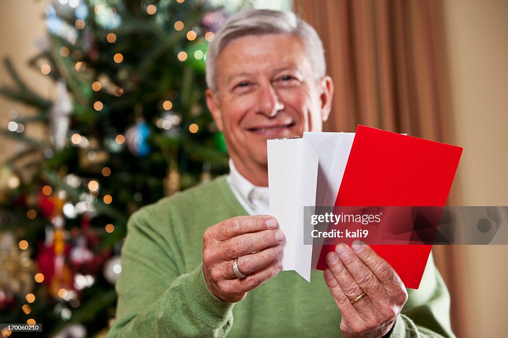 Grandfather with holiday cards by Christmas tree