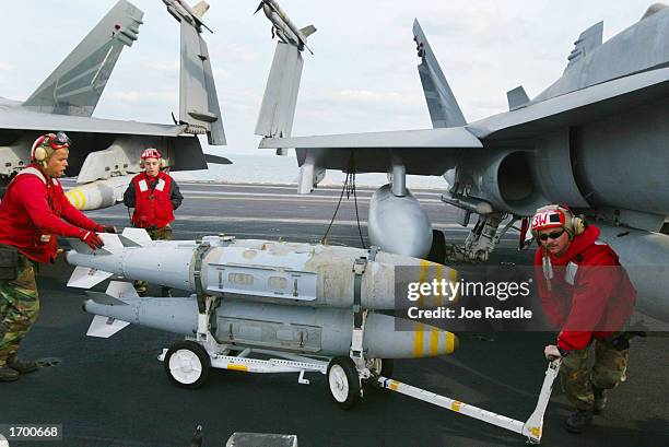 Navy weapons ordinance men wheel bombs to fighter planes on the deck of the USS Constellation December 24 , 2002 in the Persian Gulf. The war planes...