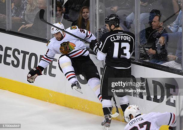 Kyle Clifford of the Los Angeles Kings checks Michal Rozsival of the Chicago Blackhawks at the end boards in the second period of Game Four of the...