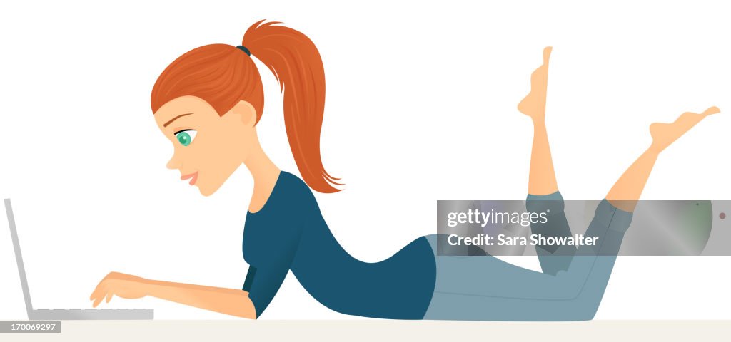 A woman lying on her stomach while using her laptop