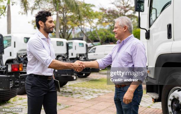 man buying a truck and closing a deal with a handshake at the dealership - veículo terrestre comercial imagens e fotografias de stock