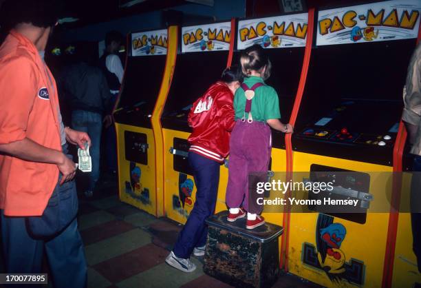 Young girls are photographed June 1, 1982 playing Pac-Man at a video arcade in Times Square, New York City.