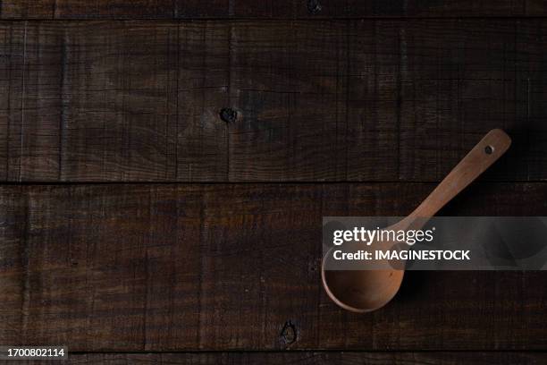 smooth wooden ladle against a textured backdrop of dark brown planks, radiating rustic elegance and natural beauty - wooden spoon stock pictures, royalty-free photos & images