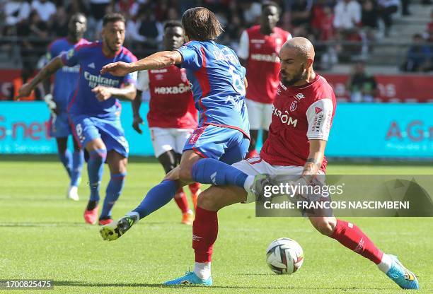 Lyon's French midfielder Maxence Caqueret fights for the ball with Reims' French midfielder Teddy Teuma during the French L1 football match between...