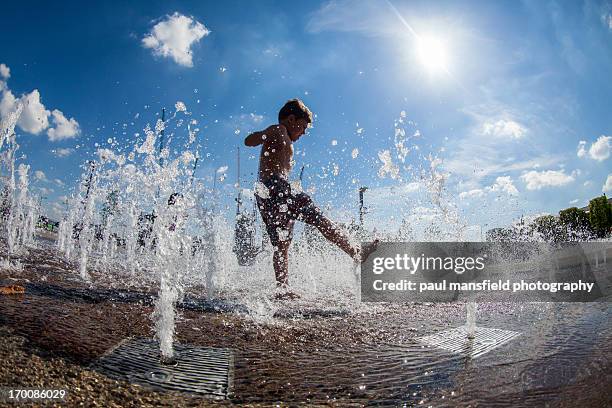 boy playing in fountain - fountain stock pictures, royalty-free photos & images