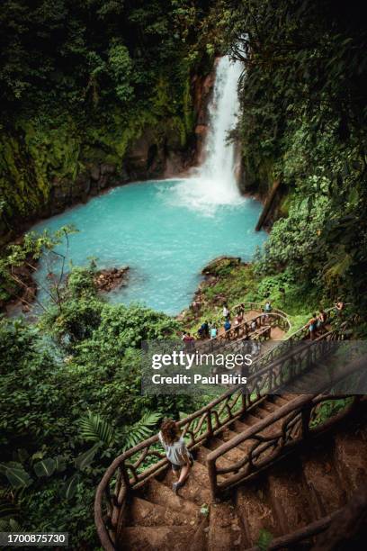 woman going down stairs to rio celeste y los teñideros waterfall, costa rica - costa rica stock pictures, royalty-free photos & images
