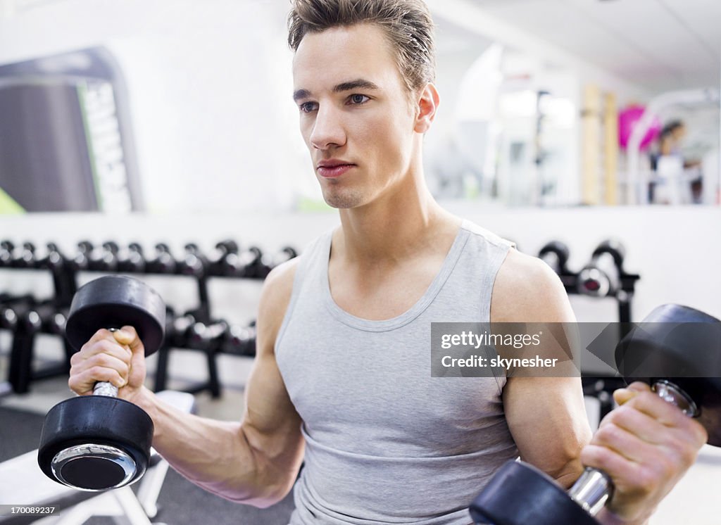 Man doing exercise with dumbbells at gym