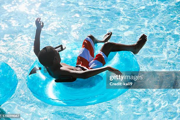 preteen african american boy floating on innertube - lazy river stock pictures, royalty-free photos & images
