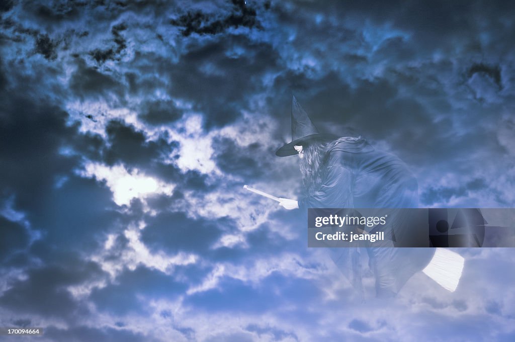 Witch flying in cloudy night sky
