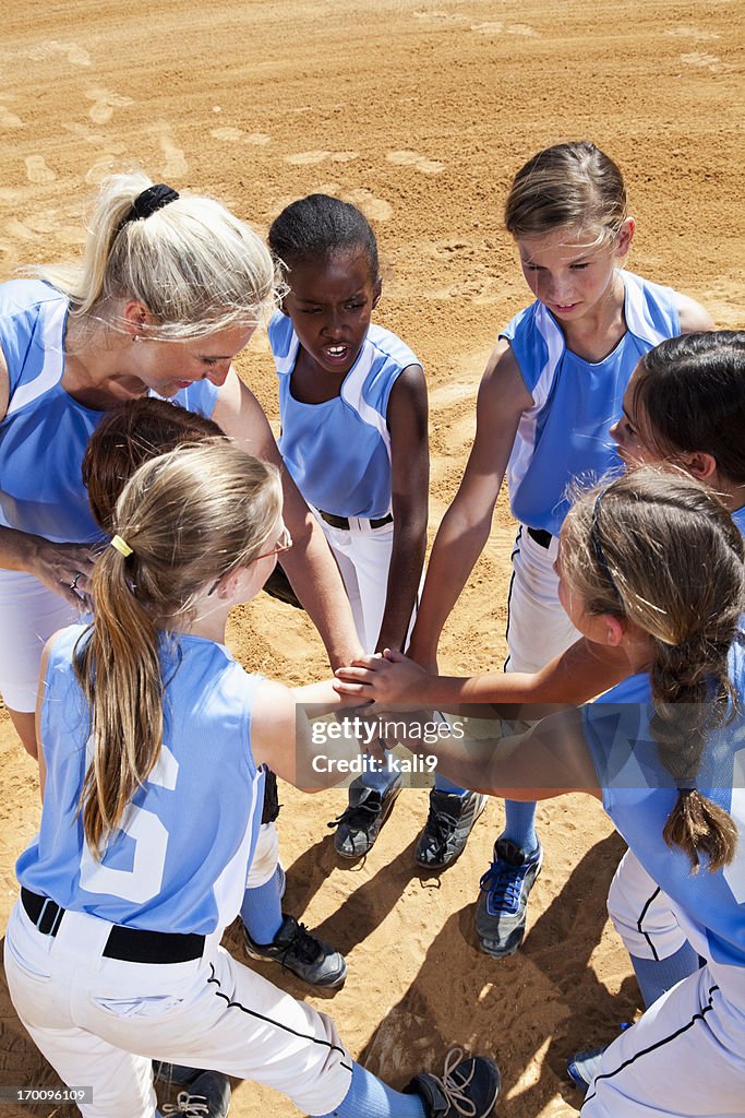Softball players with coach in huddle doing team cheer