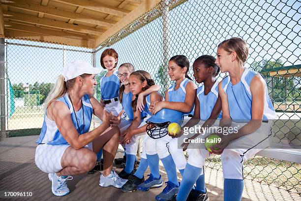 girls softball team in dugout with coach - girls softball stock pictures, royalty-free photos & images
