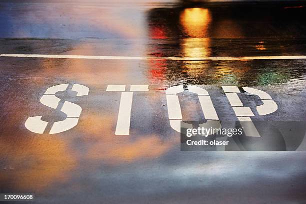 road junction, stop word, motion blurred car in pouring rain - stop enkel woord stockfoto's en -beelden