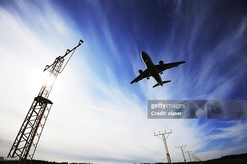 Airplane landing against dramatic sky and sun