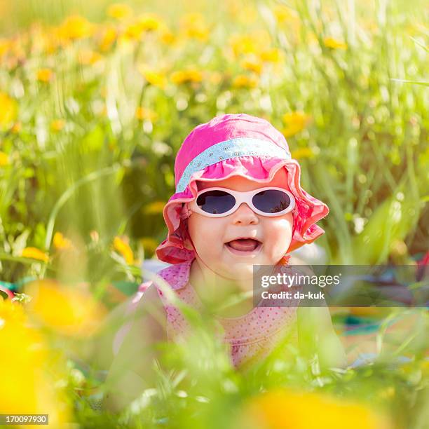 baby girl lying in a field - baby in sunglass stockfoto's en -beelden