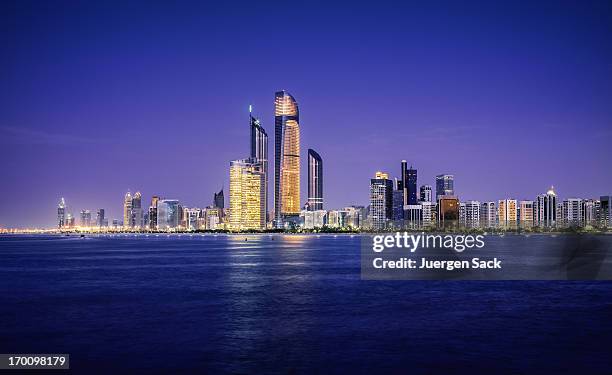 beleuchtet bei nacht skyline von abu dhabi - corniche stock-fotos und bilder