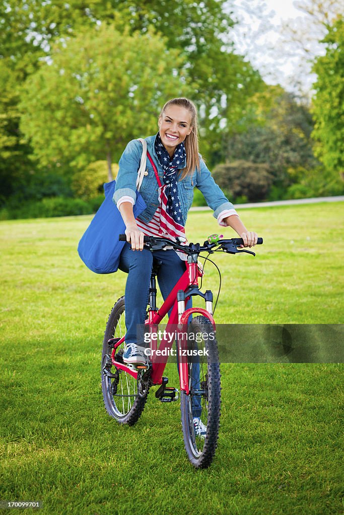 Feliz mujer joven en bicicleta en un parque