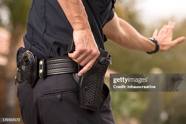 policeman preparing to draw his gun - vuurwapen stockfoto's en -beelden