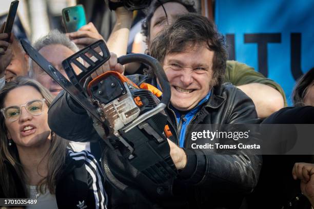 Presidential candidate Javier Milei of La Libertad Avanza lifts a chainsaw next to Buenos Aires province governor candidate Carolina Piparo of La...