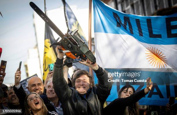 Presidential candidate Javier Milei of La Libertad Avanza lifts a chainsaw next to Buenos Aires province governor candidate Carolina Piparo of La...