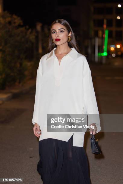 Olivia Culpo wears white oversized button shirt Khaite, black pleated transparent long skirt Khaite, black boots, Hermes bag during the Milan Fashion...