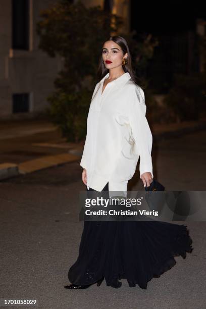 Olivia Culpo wears white oversized button shirt Khaite, black pleated transparent long skirt Khaite, black boots, Hermes bag during the Milan Fashion...