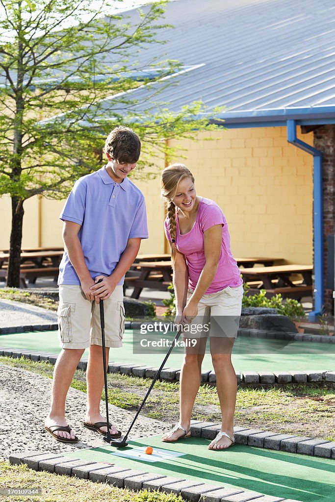 Teenage couple playing miniature golf