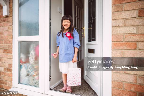 cheerful birthday girl with a gift bag arriving at front door of home after birthday party - afterr stock pictures, royalty-free photos & images